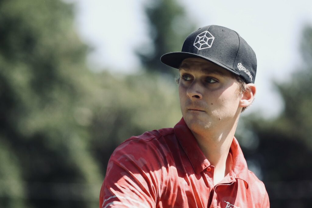 Team GRIPeq member Adam Hammes wearing a GRIPeq flat bill hat and looking off towards the left side of the frame.