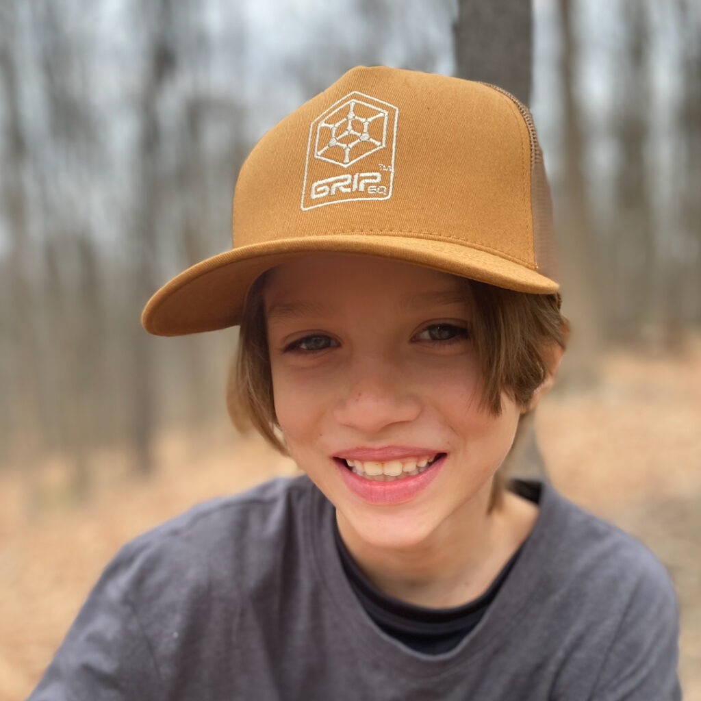 Leighton Brinster looking at the camera. He's wearing a sand GRIPeq trucker hat.