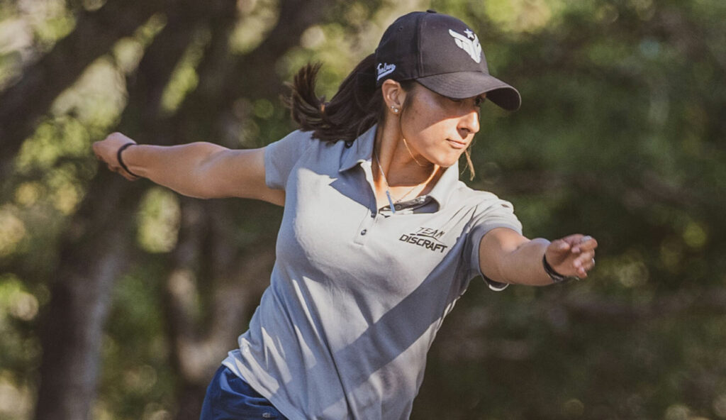 Team GRIPeq member, Alexis Mandujano, has her arms outstretched and her torso twisted, right after releasing a disc golf throw.