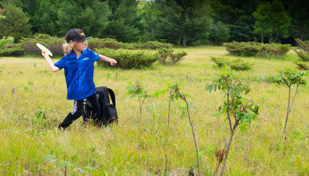 Nikko Forbes throwing a disc with a black GRIPeq bag sitting on the ground at his feet.