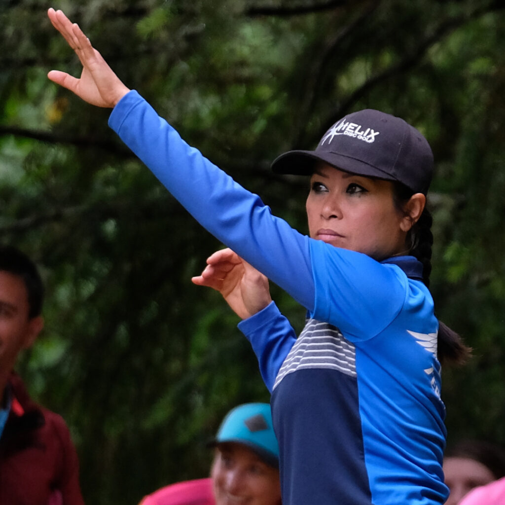 Team GRIPeq member Ohn Scoggins raises her arm in the air as she keeps her eyes on the disc that she just threw.