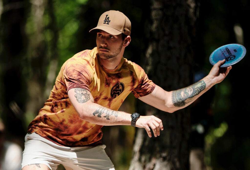 Team GRIPeq member, Austin Turner, brings his arm back to throw a forehand shot. He is wearing an LA baseball cap.