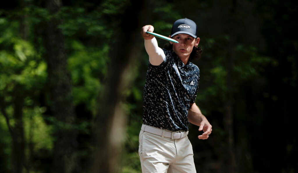 Ben Callaway looks down his arm at the disc in his hand, preparing to throw a disc.