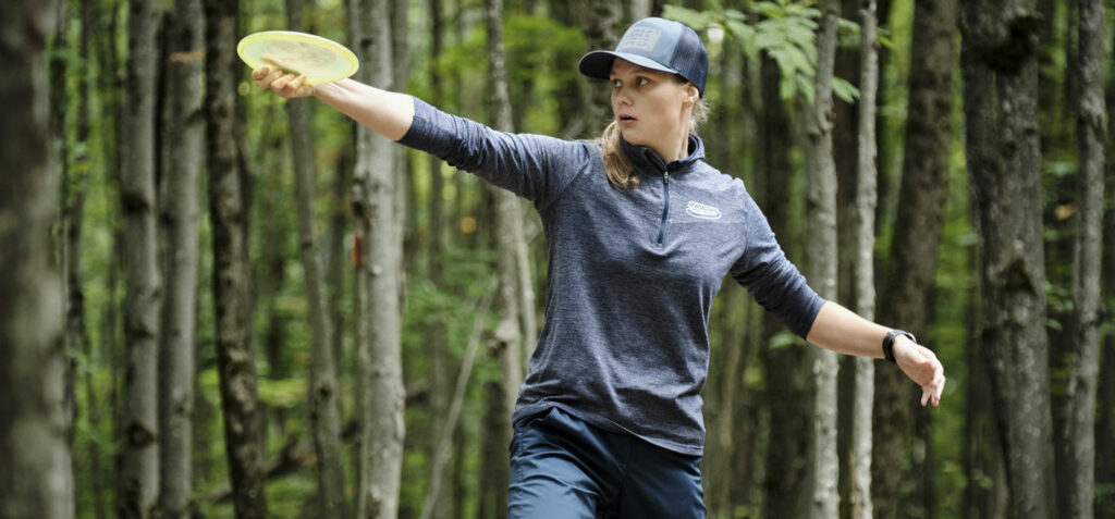 Henna Blomroos lines up a putt. A forest of trees is behind her.
