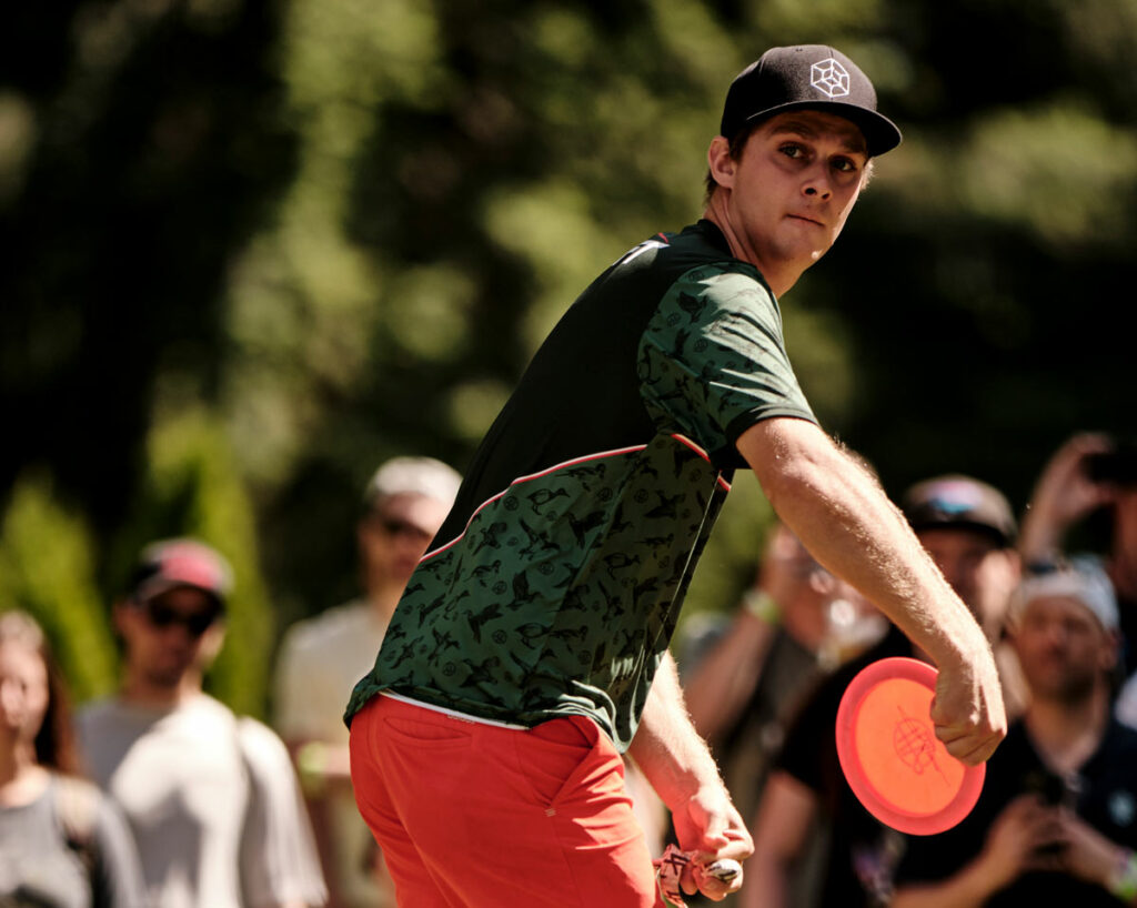 Adam Hammes, wearing a GRIPeq flat bill hat, winds his arm back as he prepares to throw a backhand shot.